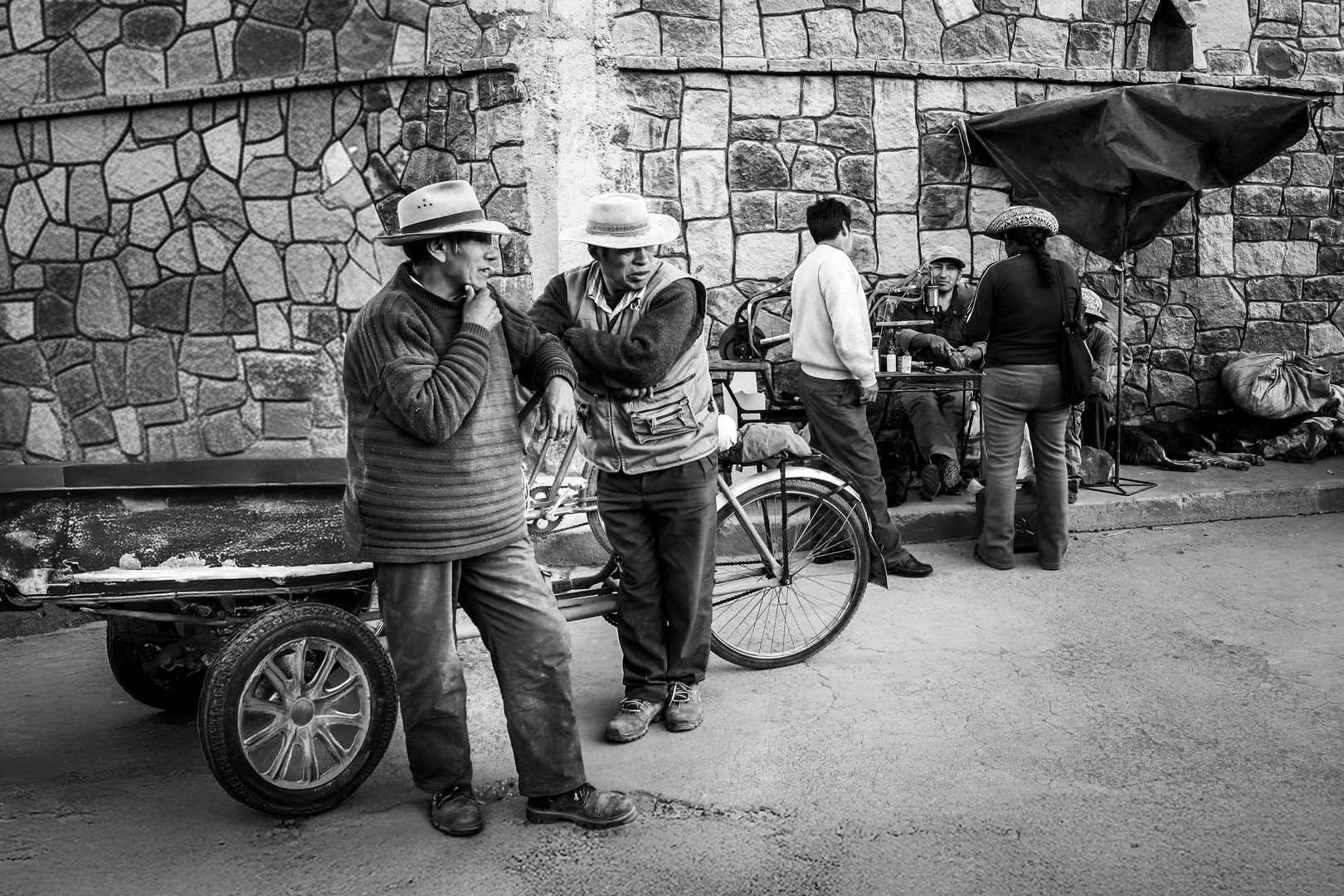 Black and white street photography of a vendor’s cart in a Peruvian market, showing the organized chaos and textures of daily trade.